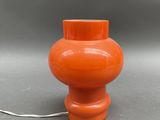 an orange vase sitting on top of a table next to a white cord