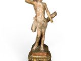 une statue ancienne représentant un homme armé d'une épée, posée sur un socle