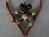 mickey mouse figurine with skis and ski poles hanging on a wall