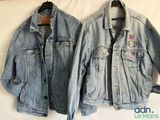 une paire de vestes en jean ornées de patchs, suspendues à un cintre