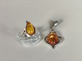 two silver and amber glass pendants on a white surface