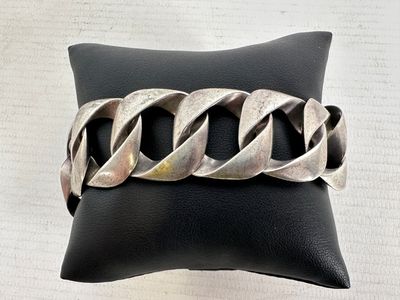 bracelet en métal argenté monté sur un cordon en cuir noir de type « coussin »