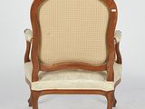 an old fashioned chair with a beige upholstered seat and arms