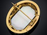 a close up of a gold and mother of pearl broochle