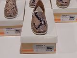 Quatre paires de chaussures sont exposées sur une surface blanche