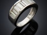 a white gold ring with baguets of diamonds on a black surface