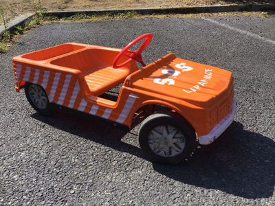 un camion jouet orange qui est garé sur le parking