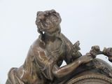 a bronze statue of a woman sitting on a clock