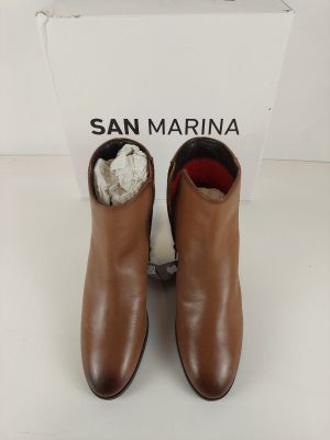 le talon d'une paire de bottes en cuir marron, avec une boîte en arrière-plan