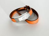 pair of orange leather bracelets with silver clasps on a white surface