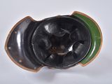 a close up of a black and green helmet on a white surface