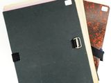 three notebooks are stacked on top of each other on a white surface