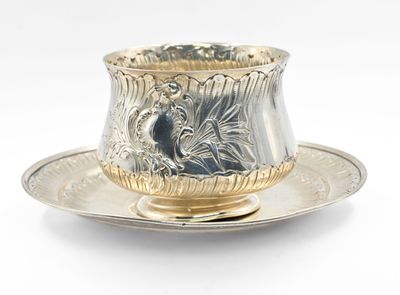 a silver cup and saucer sitting on a saucer
