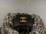 black and white tweed jacket with a gold logo on it
