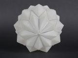 a close up of a white origami ball on a black surface