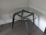 a glass table with a metal base in a corner