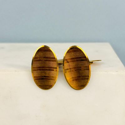 pair of gold tone cuff earrings on a white marble surface