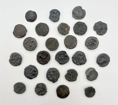 Plusieurs pièces de monnaie romaines antiques sont disposées en cercle sur une surface blanche.