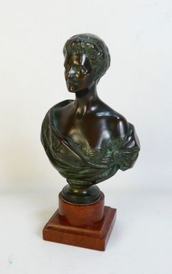 statue représentant le buste d'un homme, posée sur un socle en bois, sur fond blanc