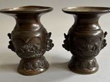 two bronze vases sitting next to each other on a table