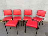 four red chairs sitting next to each other on a concrete surface