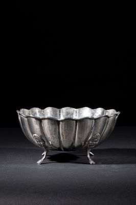 a silver bowl on a stand on a black surface