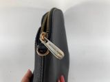 the zipper of a black purse is open with a gold zipper