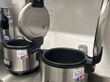 un plan de travail en acier inoxydable sur lequel sont posés des casseroles et des poêles, dans une cuisine professionnelle