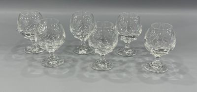 six crystal wine glasses lined up in a row on a white surface