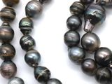 two strands of black pearl beads on a white surface