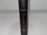 un vieux livre noir orné de lettres dorées, posé sur une surface blanche