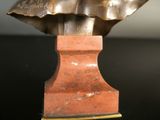 bronze bust of a woman on a marble base on a black surface