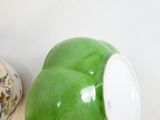 un bol vert posé à côté d'un bol blanc sur une table