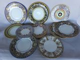 six assiettes ornées de motifs dorés, bleus et blancs sont disposées sur un fond blanc