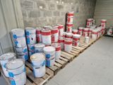 de nombreux seaux de peinture posés sur une palette dans un entrepôt