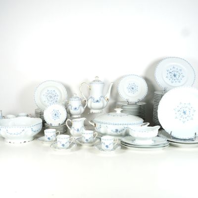 beaucoup d'assiettes et de tasses blanches et bleues sur la table