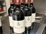 six bottles of red wine are lined up on a metal counter
