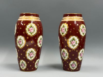 une paire de vases rouges ornés de fleurs dorées et roses