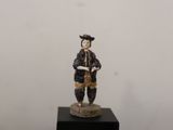 une figurine représentant un homme tenant un livre, posée sur un socle noir