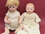 two dolls sitting next to each other on a red surface