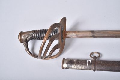 une petite épée et un petit objet métallique posés sur une surface blanche