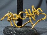 a close up of a gold brooch on a black stand