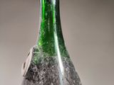 a green bottle with dirt on it sitting on a table
