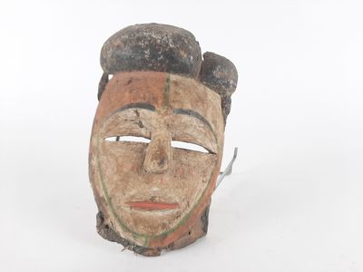 a wooden mask with a face on it on a white surface