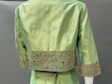 an image of a mannequin wearing a green dress with gold embroiderys