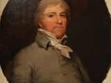 portrait d'un homme vêtu d'un manteau gris et d'une chemise à col blanc