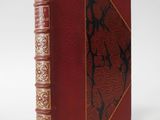 an old book with a red cover and gold trim on it