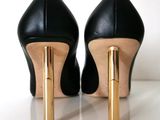 pair of black and gold high heeled shoes on a white surface