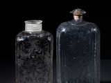 two clear glass bottles sitting next to each other on a black surface
