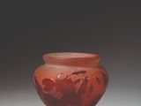 a red vase sitting on top of a white table